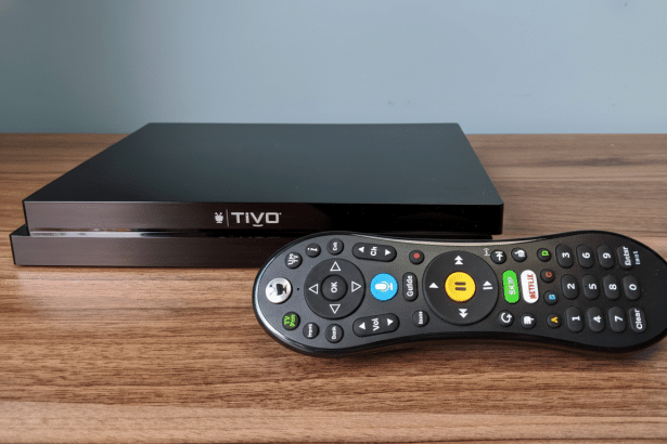 A black Ti Vo box and a black TiVo remote control resting on a wooden surface.