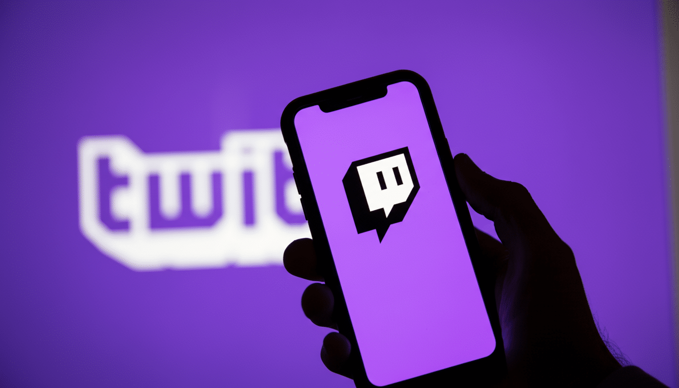A hand holding a smartphone displaying the Twitch logo, with the Twitch brand name blurred in the background, set to a 16: 9 aspect ratio.