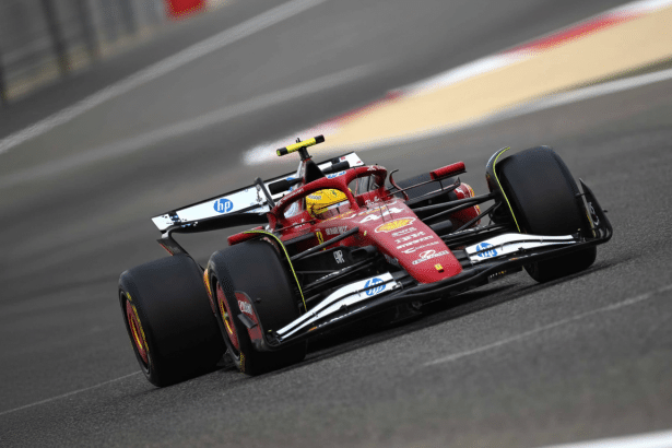 ** A red Ferrari Formula 1 car speeding around a track, viewed from a slight angle. **