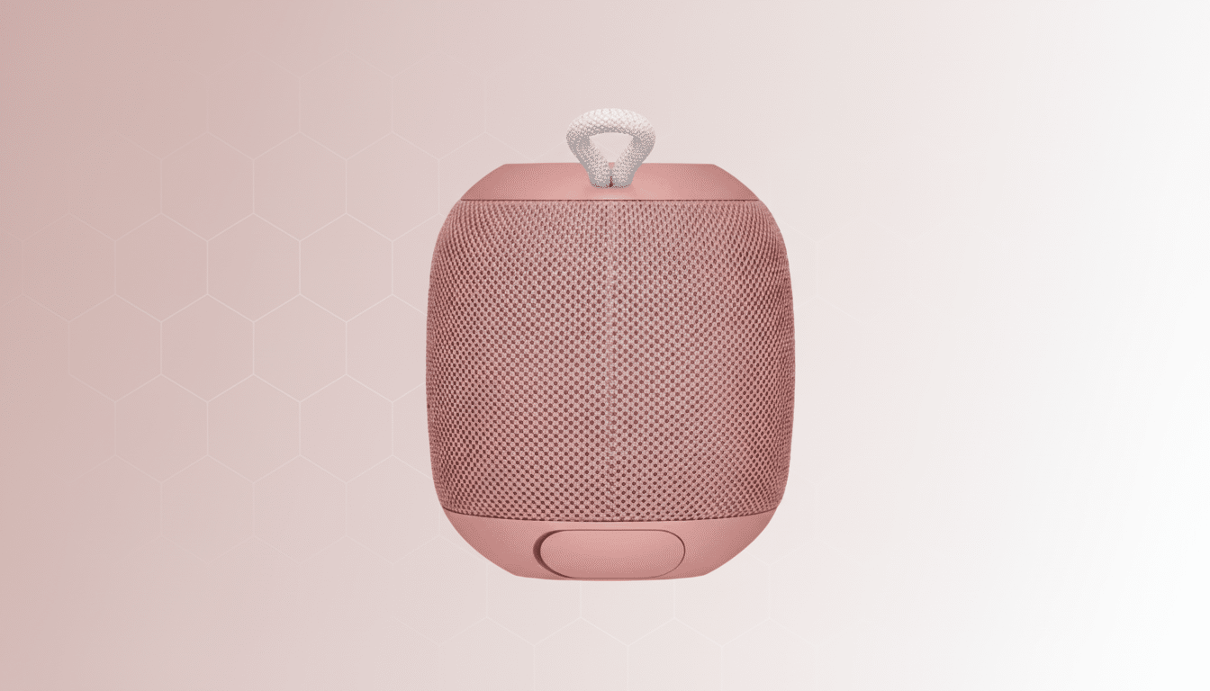 alt = A rose pink portable Bluetooth speaker with a white braided loop, presented on a soft pink gr