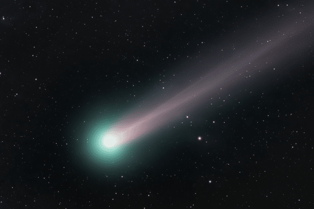 A vibrant comet with a glowing greenish -blue head and a long , diffuse pinkish- purple tail extending across a dark, star-filled night sky. Filename : vibrant comet night sky.png