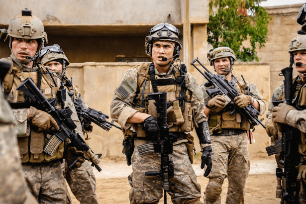 A group of soldiers in combat gear standing outdoors, resized to a 1 6: 9 aspect ratio with enhanced professional quality.
