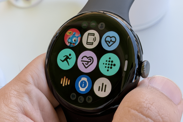 A close-up of a hand holding a Google Pixel Watch, displaying various app icons on its circular screen.