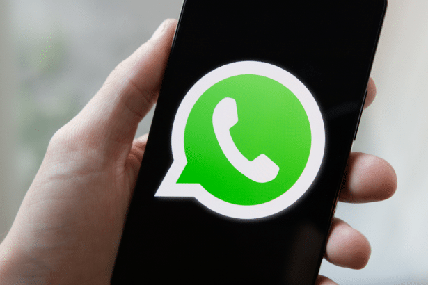 A hand holding a smartphone displaying the WhatsApp logo on its screen. Filename : whatsapplogo onsmartphone .png