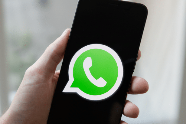 A hand holding a smartphone displaying the WhatsApp logo on its screen. Filename : whatsapplogo onsmartphone .png