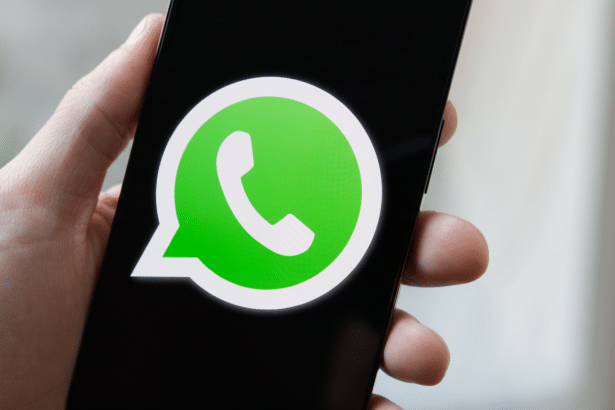 A hand holding a smartphone displaying the WhatsApp logo on its screen. Filename : whatsapplogo onsmartphone .png