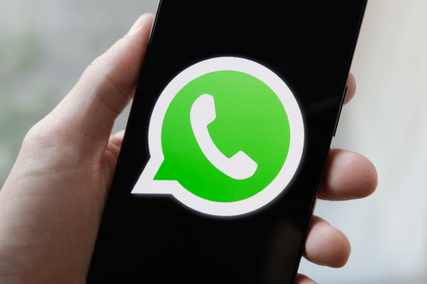 A hand holding a smartphone displaying the WhatsApp logo on its screen, resized to a 16:9 aspect ratio.