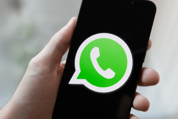 A hand holding a smartphone displaying the WhatsApp logo on its screen. The image has been resized to a 16: 9 aspect ratio, professionally enhanced, with the original background maintained .