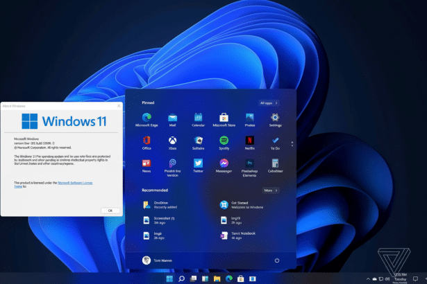 Screenshot of Windows 11 desktop with the About Windows dialog box open, showing the version Dev ( OS Build 21 996. 1). The background features a dark blue abstract wallpaper. The start menu is also open, displaying pinned apps and recommended documents .
