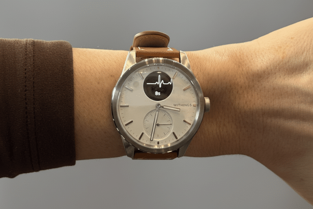 A professional shot of a With ings smartwatch on a person's wrist , displaying a heart rate graph.