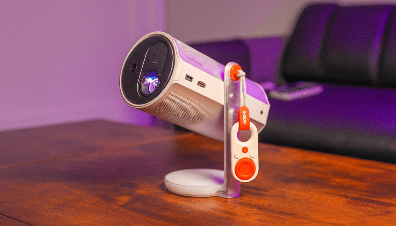 A white X GIMI Halo + portable projector with an orange remote control attached, sitting on a wooden table with a blurred purple background.