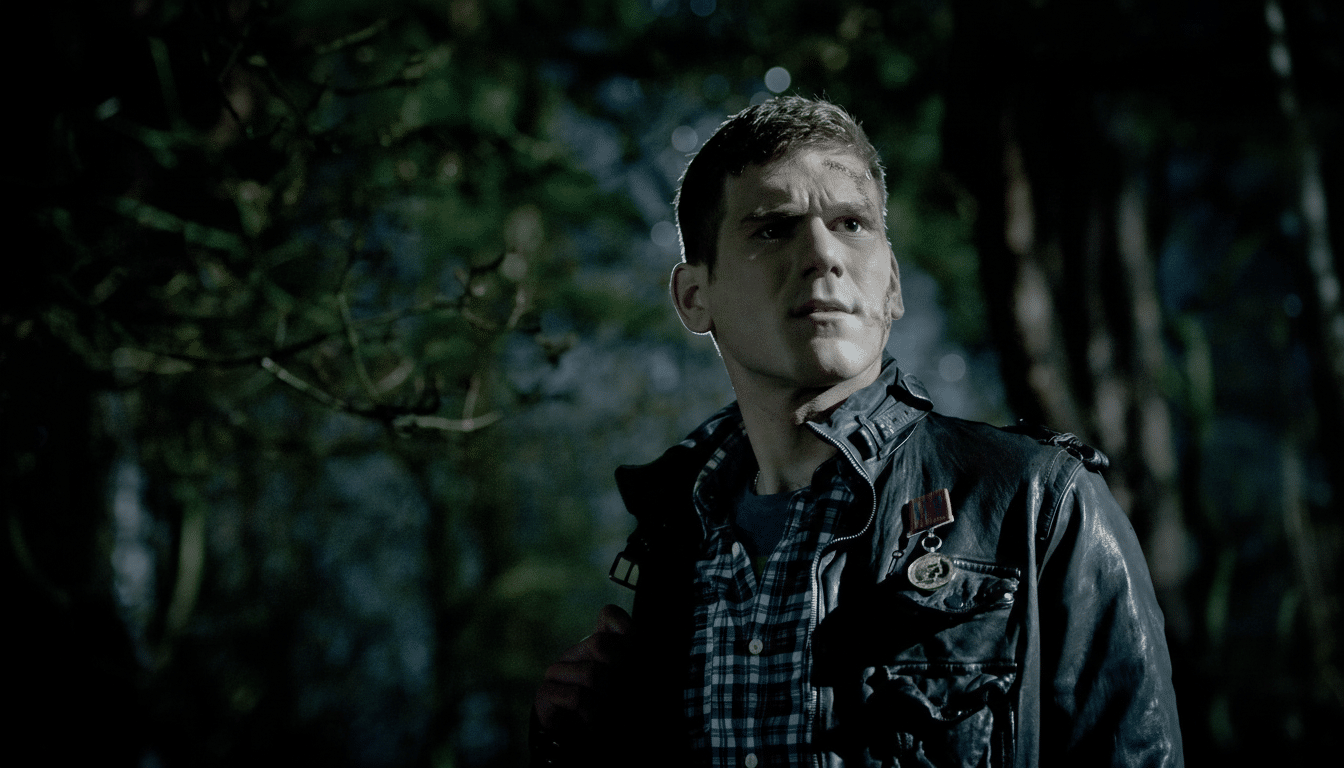A young man with facial wounds and a leather jacket looking intently into the distance in a dimly lit, forested setting.
