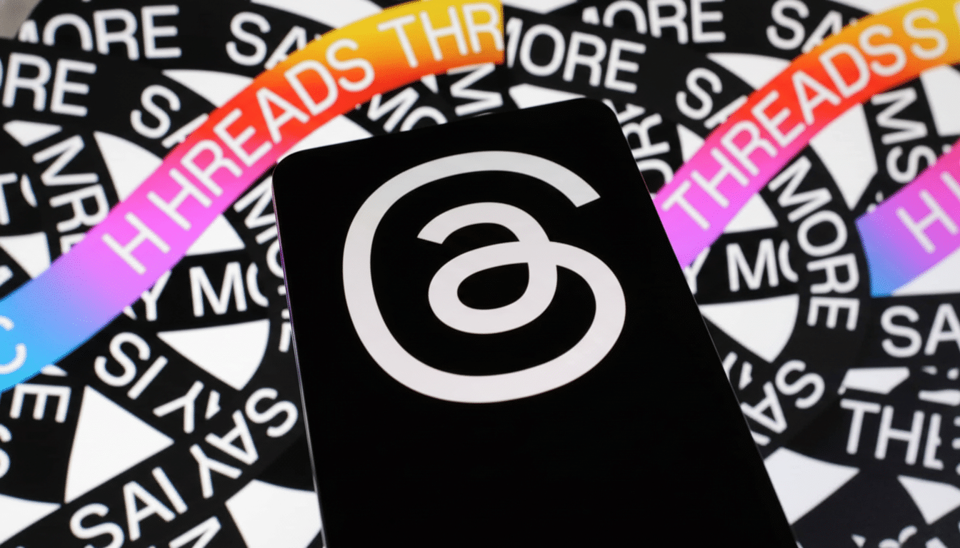A smartphone displaying the Threads app logo, a white circular a symbol, against a background of white text on black reading THREADS and SAY MORE.