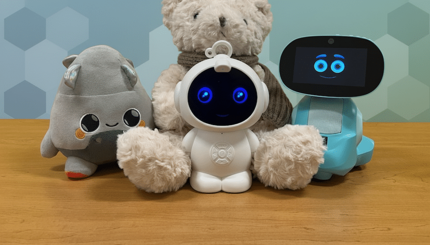 A white robot with blue eyes and fluffy arms sits between a gray plush toy and a blue robot with a screen face, in front of a teddy bear, all on a wooden surface with a blue and gray patterned background.