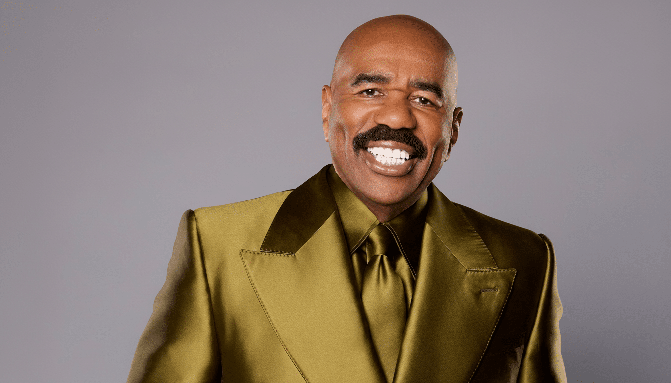 Steve Harvey smiling in a gold suit against a gray background.