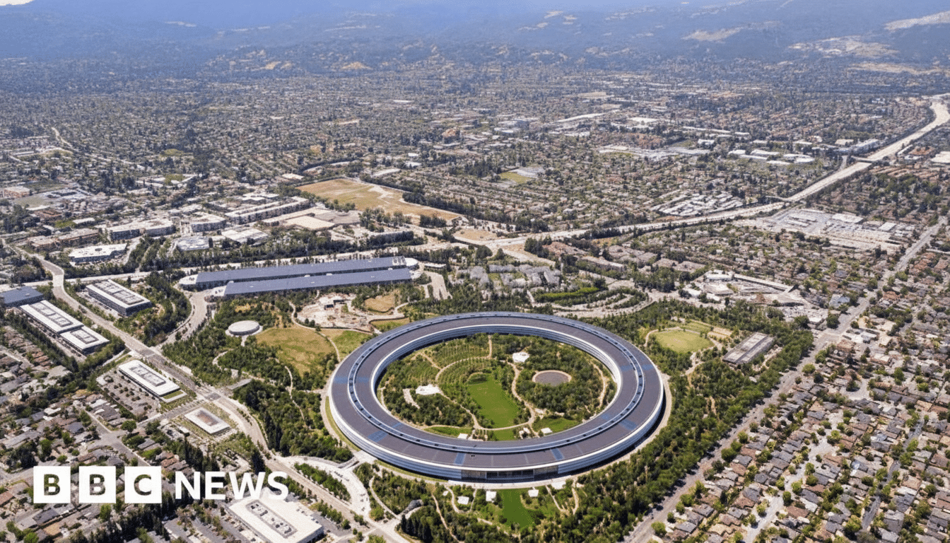 An aerial view of Apple Park, a large circular building surrounded by green spaces and a sprawling urban landscape under a clear sky.