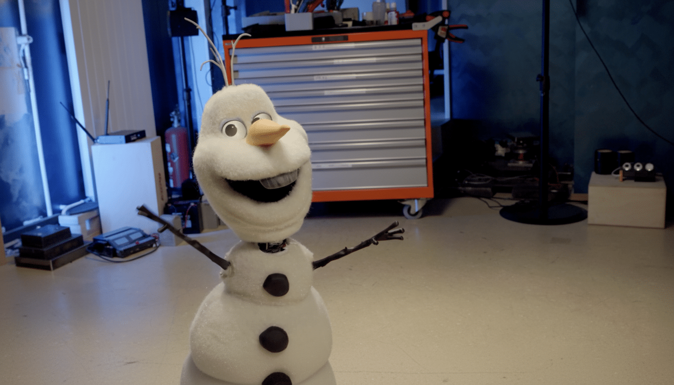 A plush Olaf snowman toy stands in a room with a tool chest in the background, resized to a 16:9 aspect ratio.