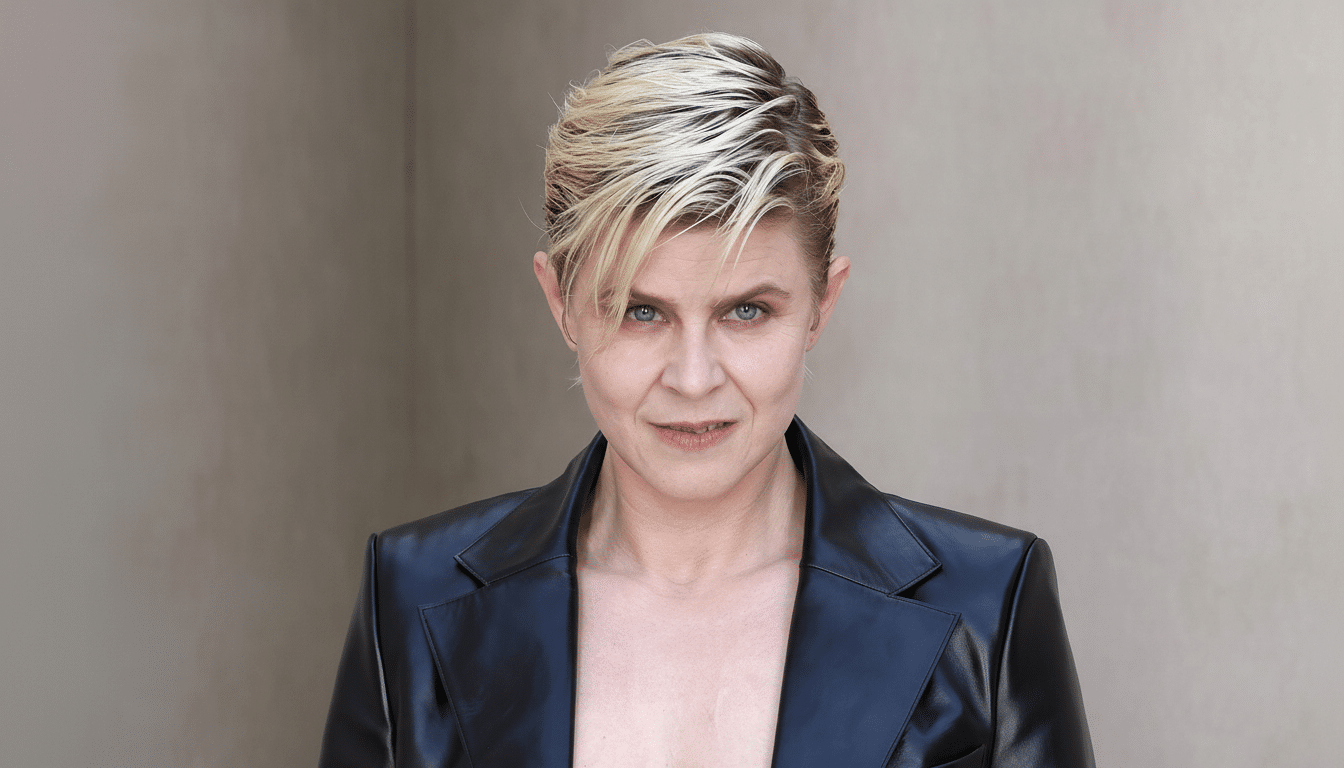 A woman with short, spiky blonde hair and a black leather jacket looks directly at the viewer.