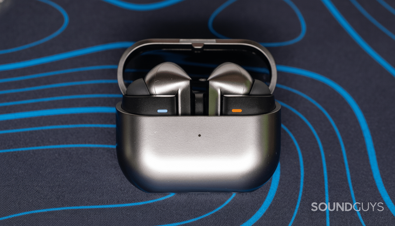 A pair of silver wireless earbuds in an open charging case, resting on a dark blue surface with light blue wavy lines.