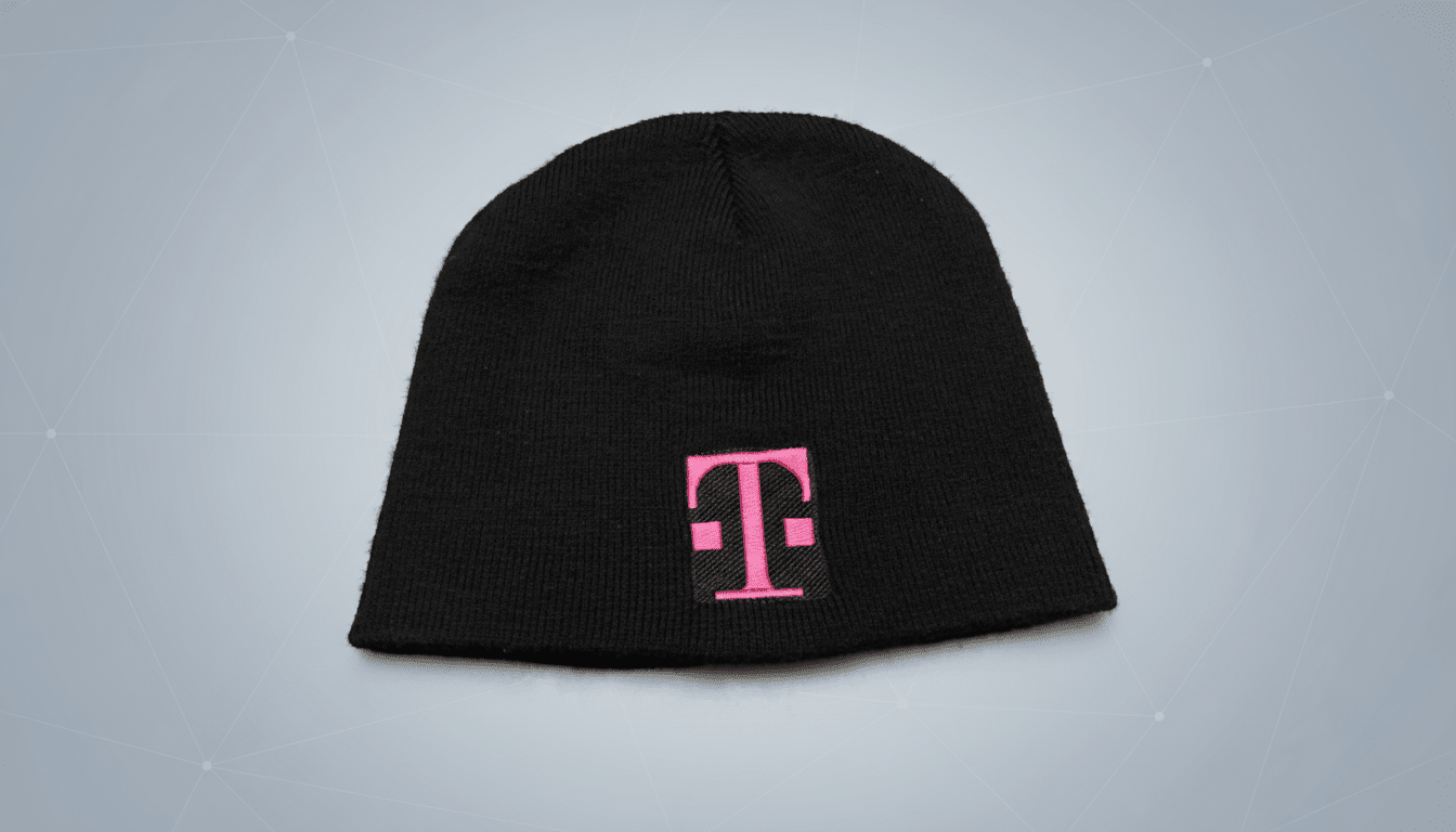 A black beanie with a pink T-Mobile logo embroidered on the front, presented on a professional light gray background with a subtle geometric pattern.