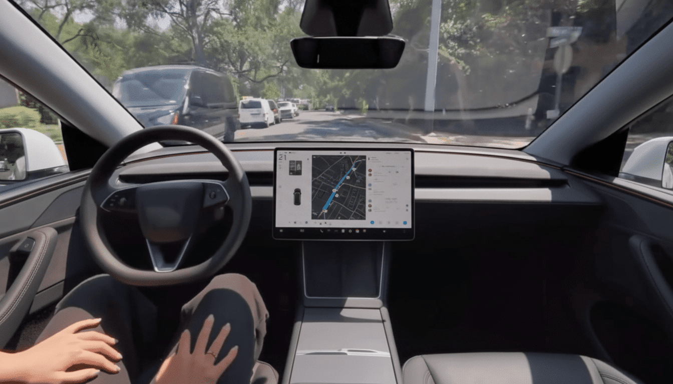 A persons hands resting on their lap inside a car, with a steering wheel and a large central display showing a map.