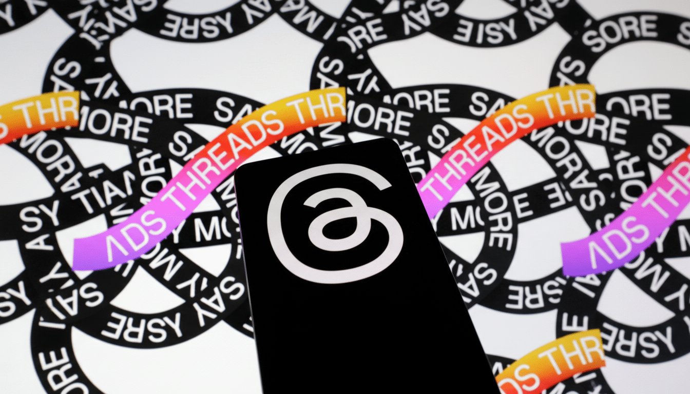 A smartphone displaying the Threads app logo, a white a on a black background, is positioned in front of a blurred background with repeating THREADS text in a circular pattern.