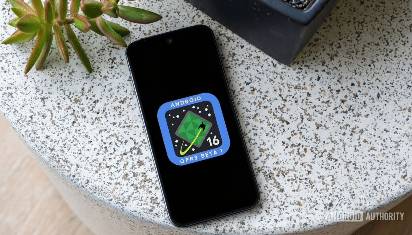 A smartphone displaying the Android QPR3 Beta 1 logo on its screen, set against a speckled white surface with a green succulent plant and a dark pot in the background.