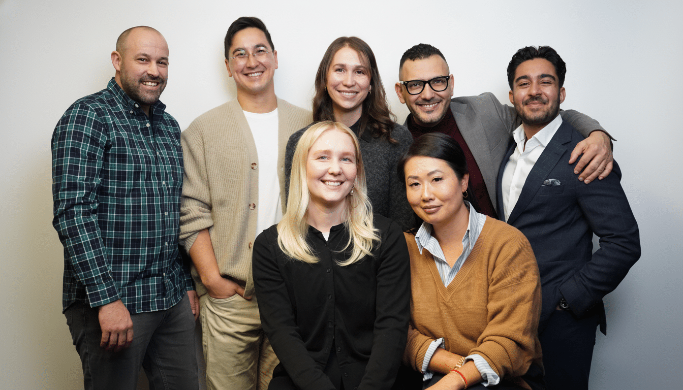 A group of seven diverse professionals smiling at the camera, resized to a 16:9 aspect ratio with the original background maintained.