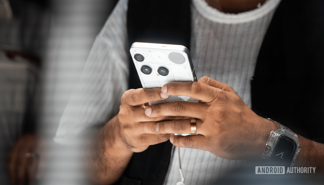 A persons hands holding a white smartphone with multiple camera lenses, resized to a 16:9 aspect ratio.