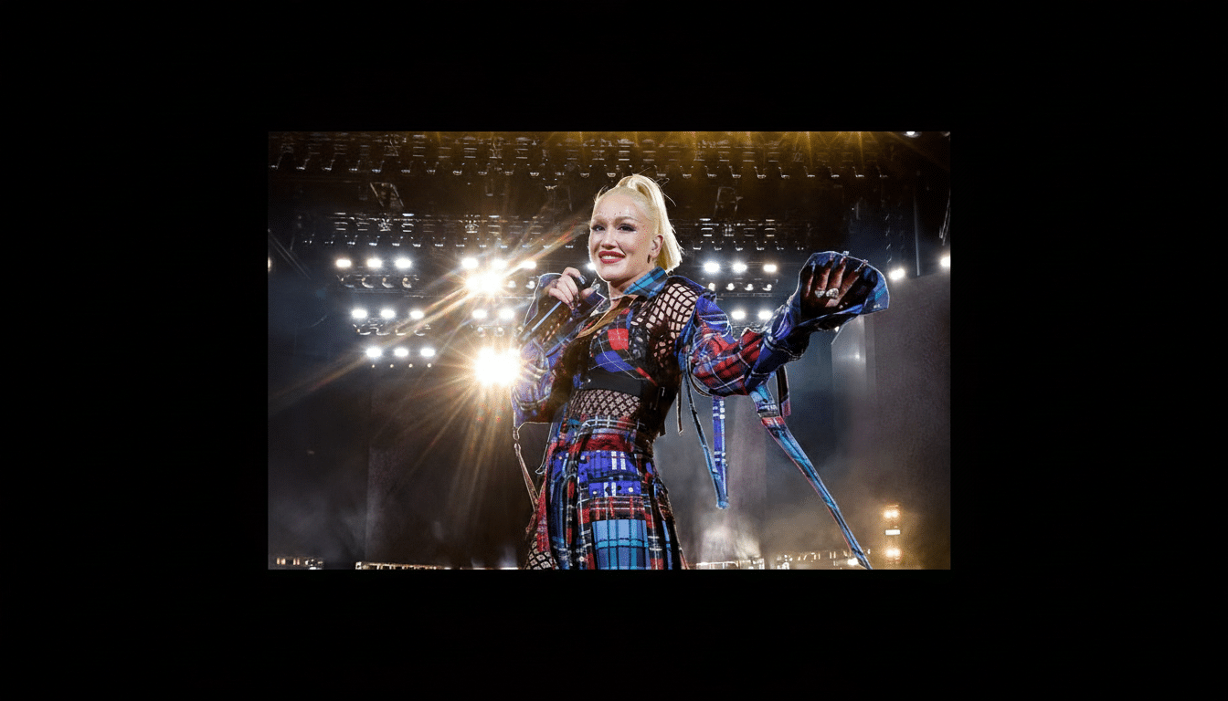 Gwen Stefani performing on stage, wearing a blue and red plaid outfit, with bright stage lights in the background.