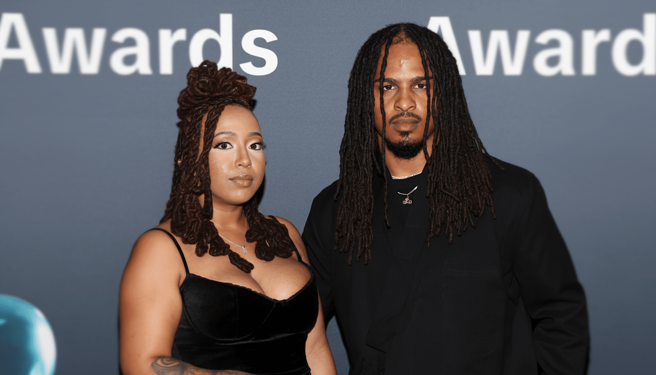 A man and a woman with dreadlocks stand side-by-side against a blurred background that reads Awards.