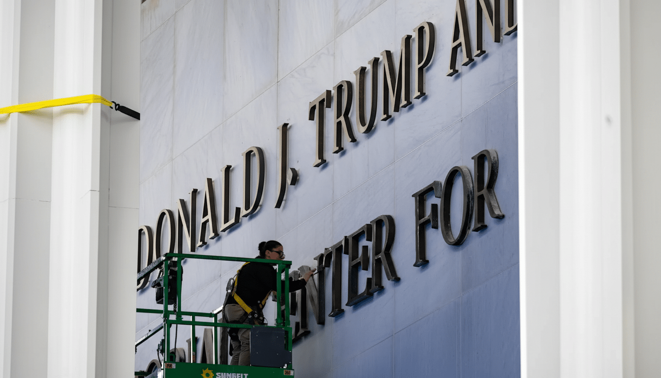 A person on a lift cleaning large letters that spell DONALD J. TRUMP AND CENTER FOR on the side of a marble building.