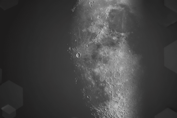 A professionally enhanced image of the moon, resized to a 16:9 aspect ratio, with a soft, dark gray background featuring subtle hexagonal patterns. The moons surface, with its craters and textures, is prominently displayed on the right side of the frame.