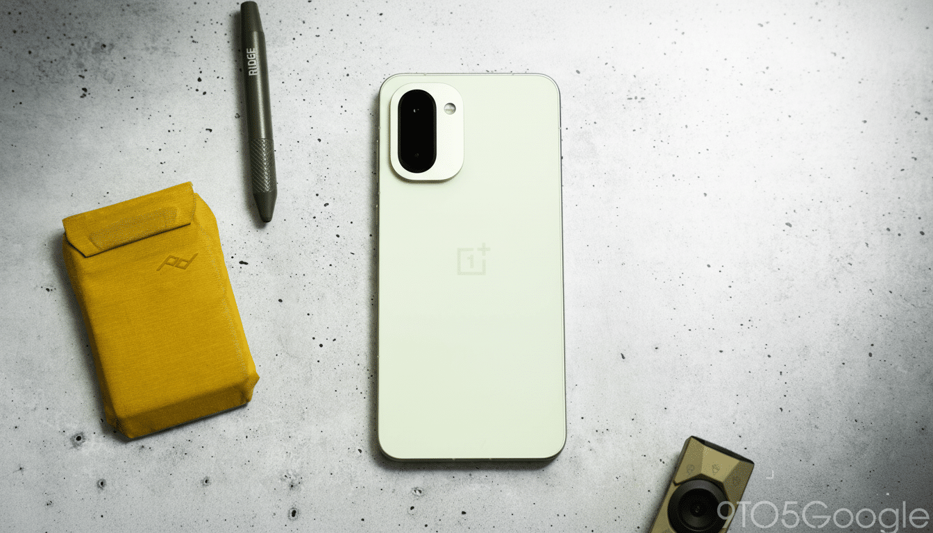 A light green smartphone, a yellow wallet, and a green pen are arranged on a speckled gray surface.