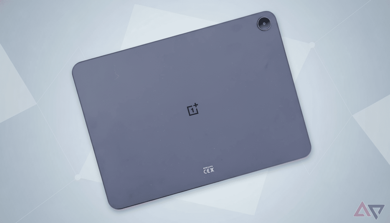 A dark gray OnePlus tablet with a camera lens in the top right corner, set against a professional light gray background with subtle geometric patterns.