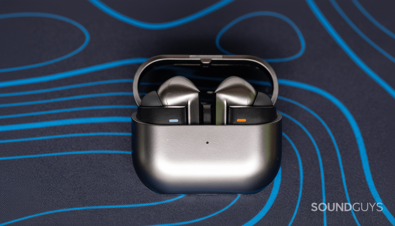 A pair of silver wireless earbuds in an open charging case, resting on a dark blue surface with light blue wavy lines.