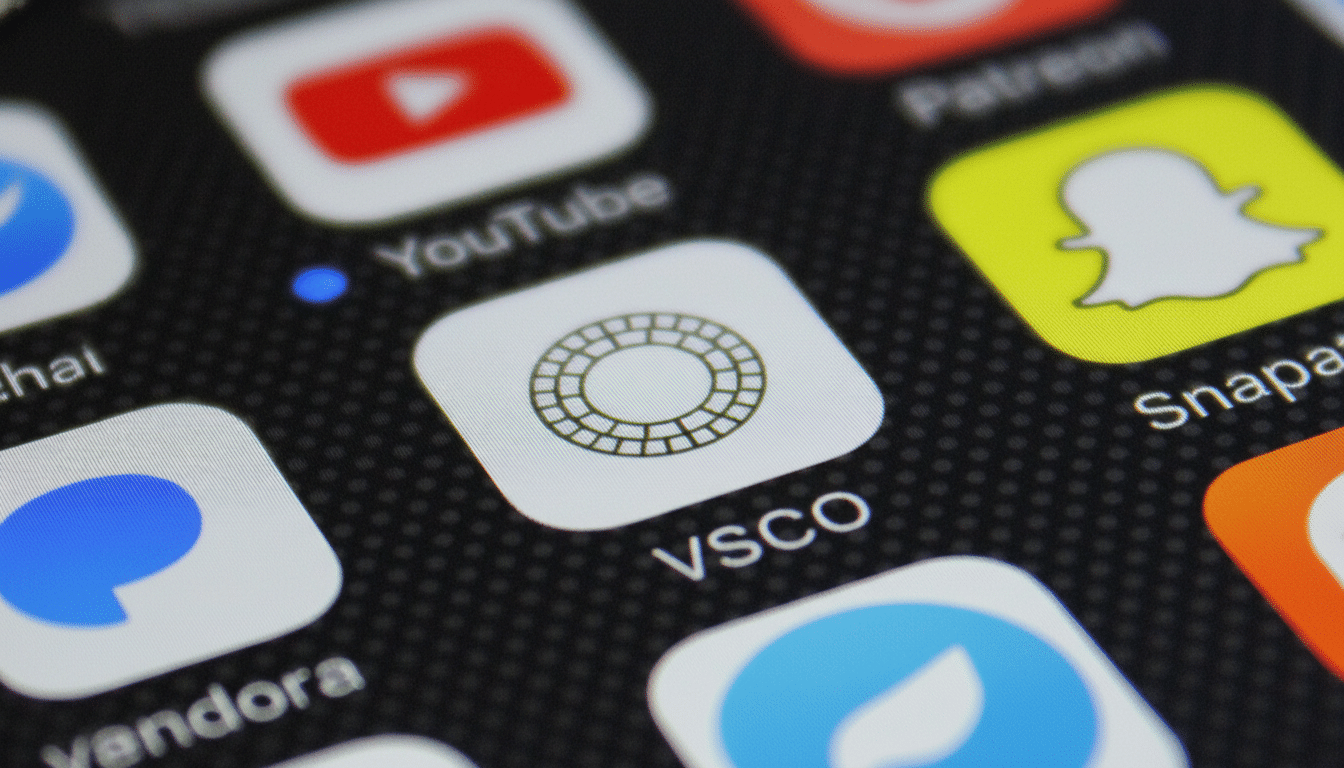 A close-up of a smartphone screen displaying app icons, with the VSCO app icon prominently featured in the center, surrounded by other app icons like YouTube, Snapchat, and Pandora.