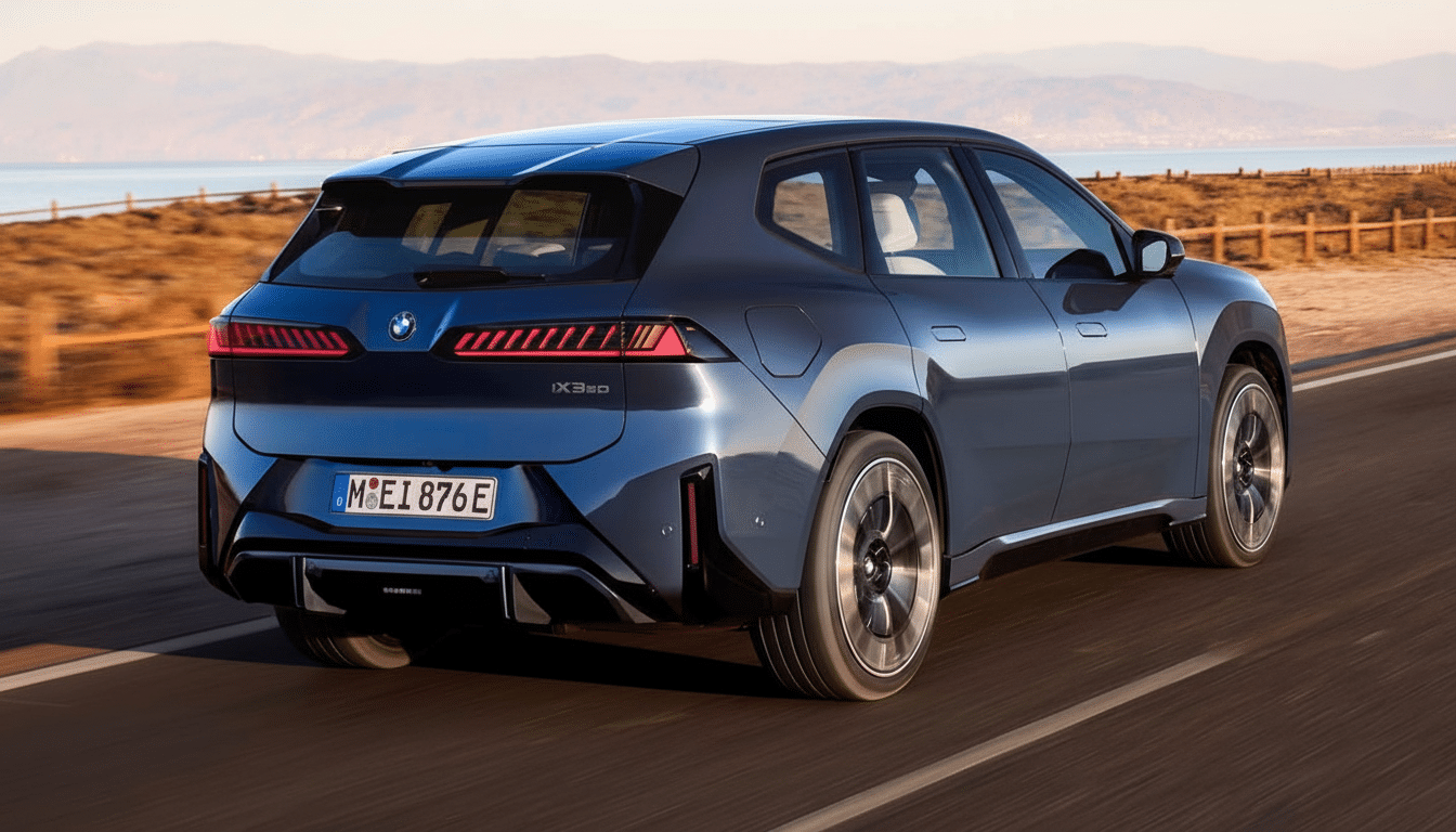 A dark blue BMW iX3 electric SUV driving on a coastal road with mountains and the sea in the background, resized to a 16:9 aspect ratio.
