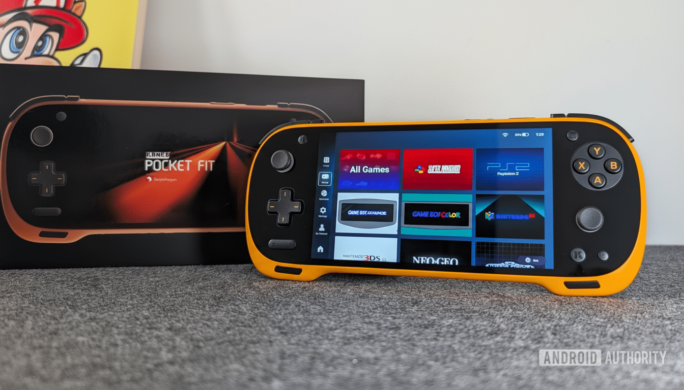 A black and orange handheld gaming device with a screen displaying various game emulators, next to its black packaging box.