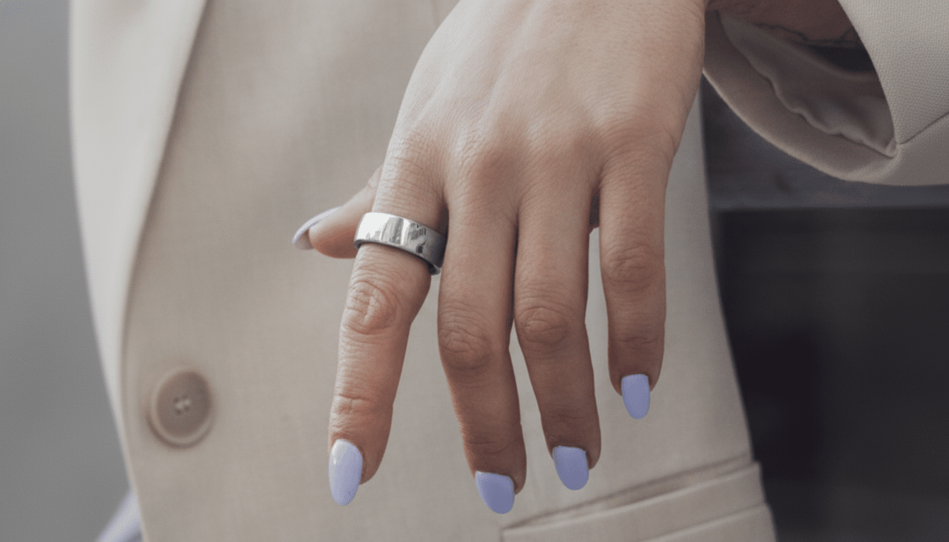 A close-up of a hand with light purple nail polish wearing a silver ring, set against a light beige blazer.
