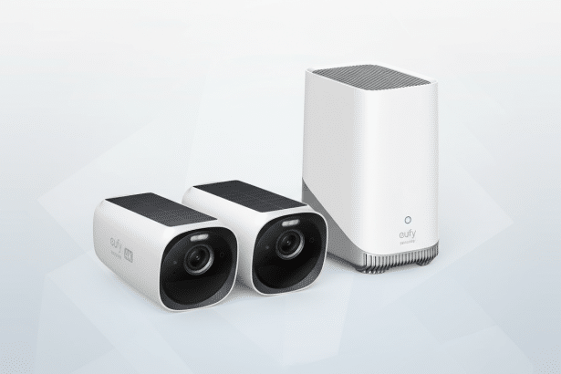 A professional 16:9 aspect ratio image of a white Eufy security system, featuring two cameras with solar panels and a base station, set against a clean, light gray gradient background.