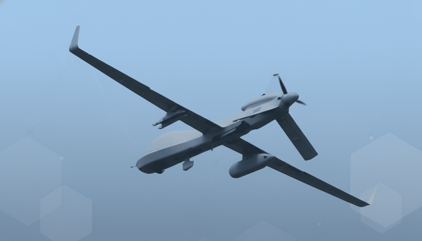 A gray drone with long wings and a propeller on its tail, flying against a clear blue sky with subtle hexagonal patterns.