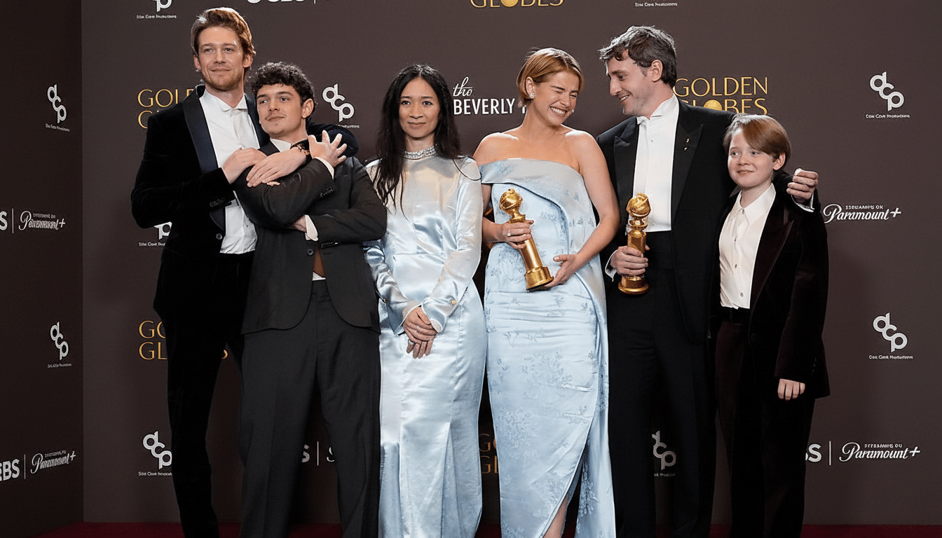A group of six people, including actors and crew, pose on a red carpet in front of a Golden Globes backdrop. Two individuals in the center are holding Golden Globe awards.