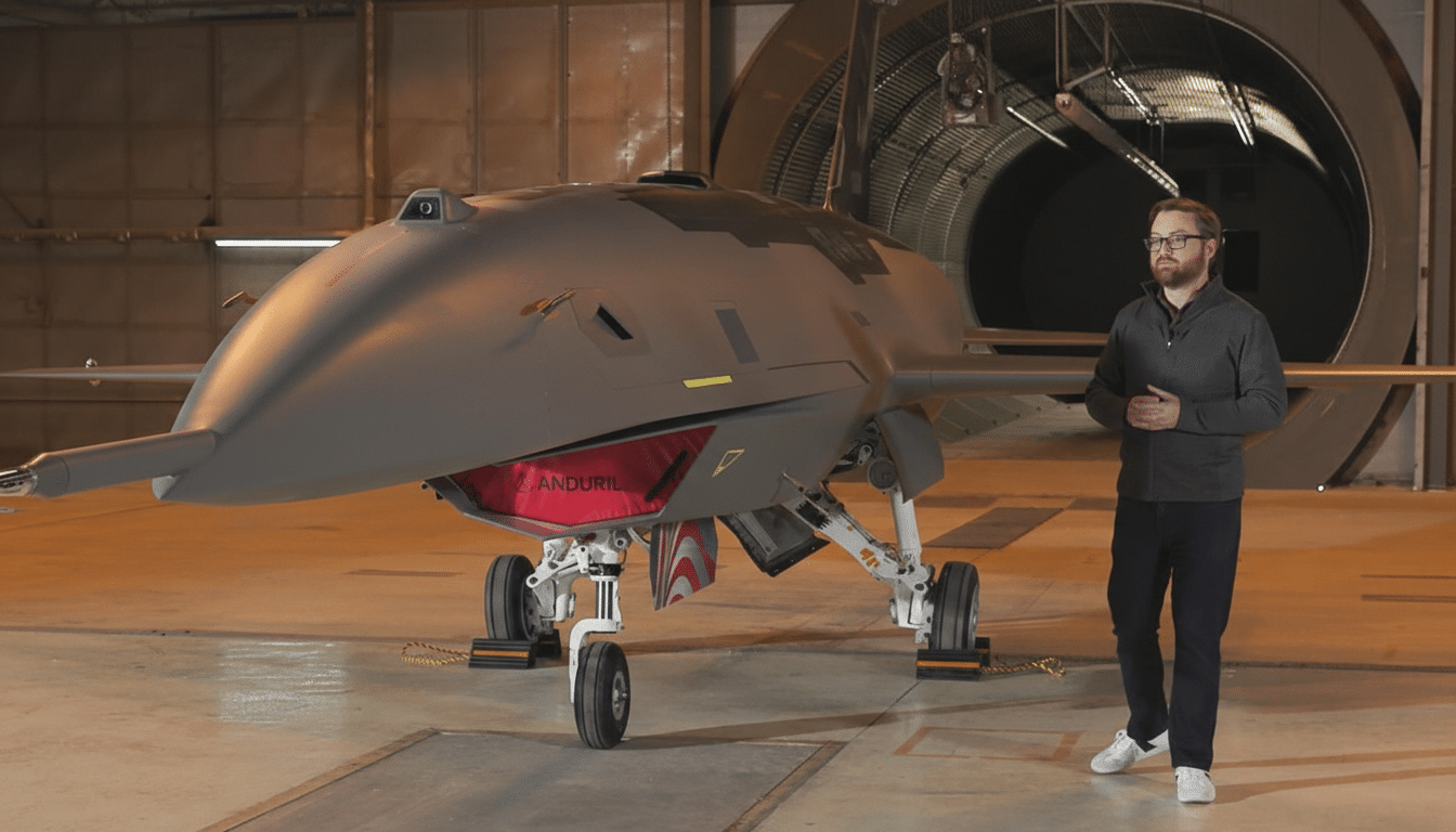 A man stands next to a large, gray unmanned aerial vehicle (UAV) in a hangar.