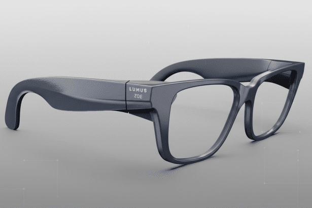 A pair of dark gray smart glasses with LUMUS ZOE written on the side, presented on a professional gray background with subtle geometric patterns.