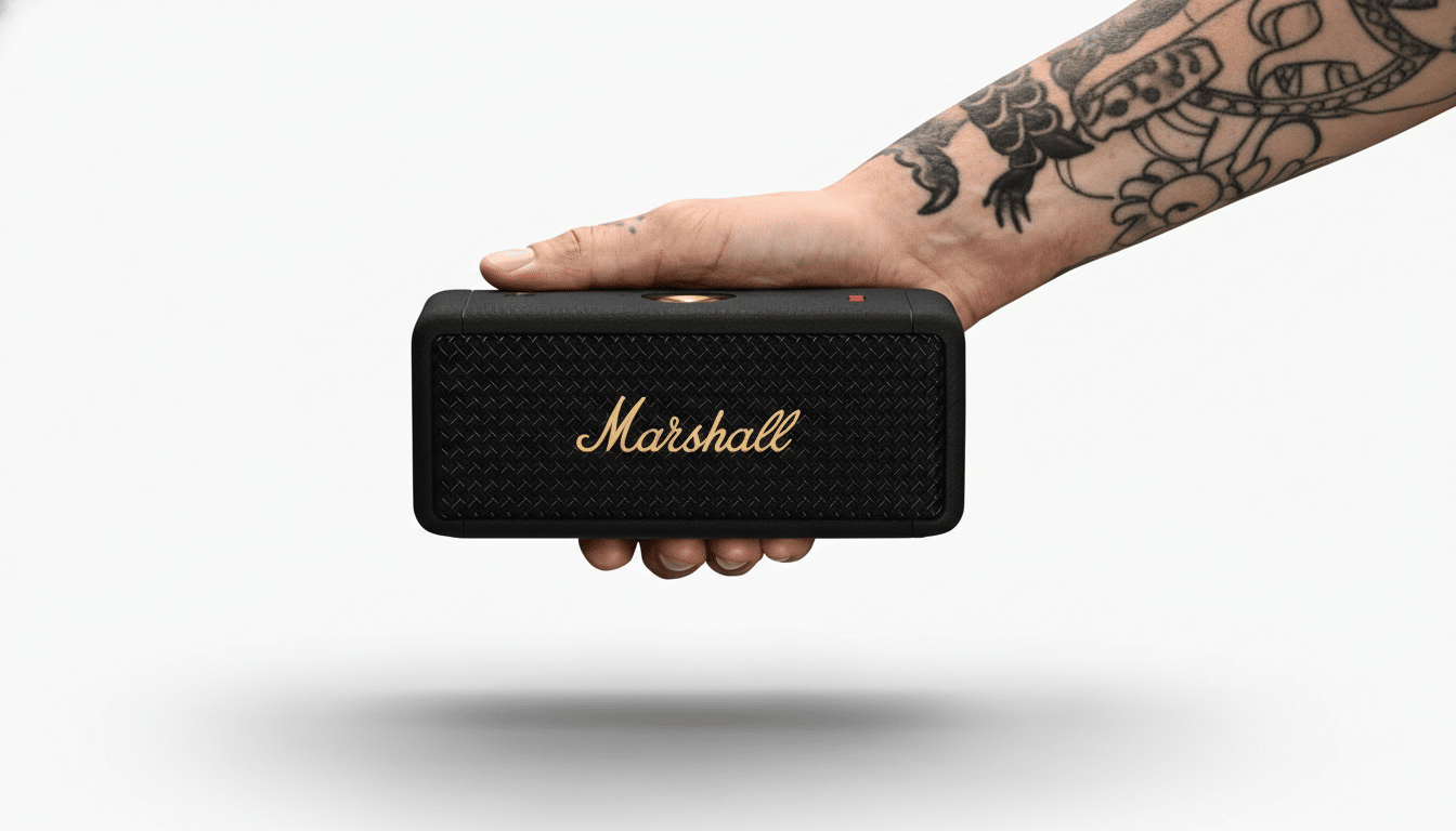 A tattooed hand holding a black Marshall portable speaker with a gold logo, presented on a clean white background.