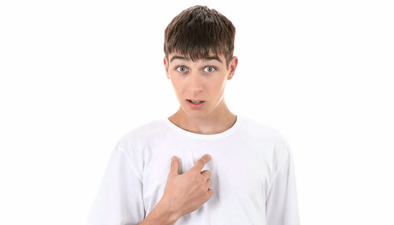 A young man with brown hair and a white t-shirt, pointing to his chest with a surprised expression, against a white background.