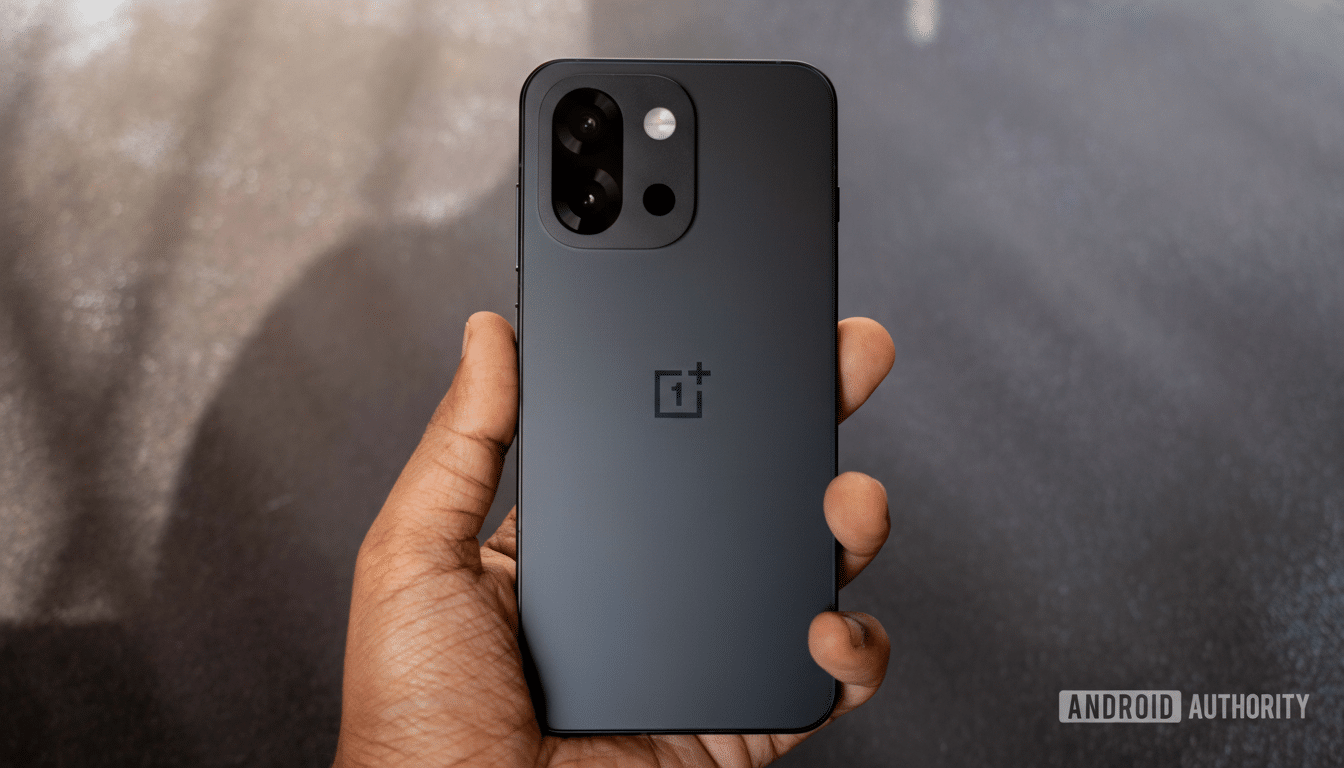 A hand holding a black OnePlus smartphone, resized to a 16:9 aspect ratio with the original background maintained.