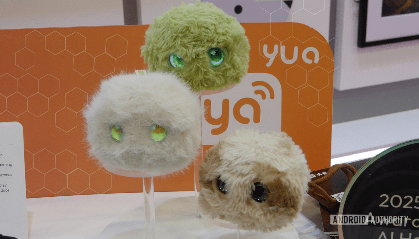 Three fluffy, round robots with glowing eyes on display, with an orange background featuring the yua logo.