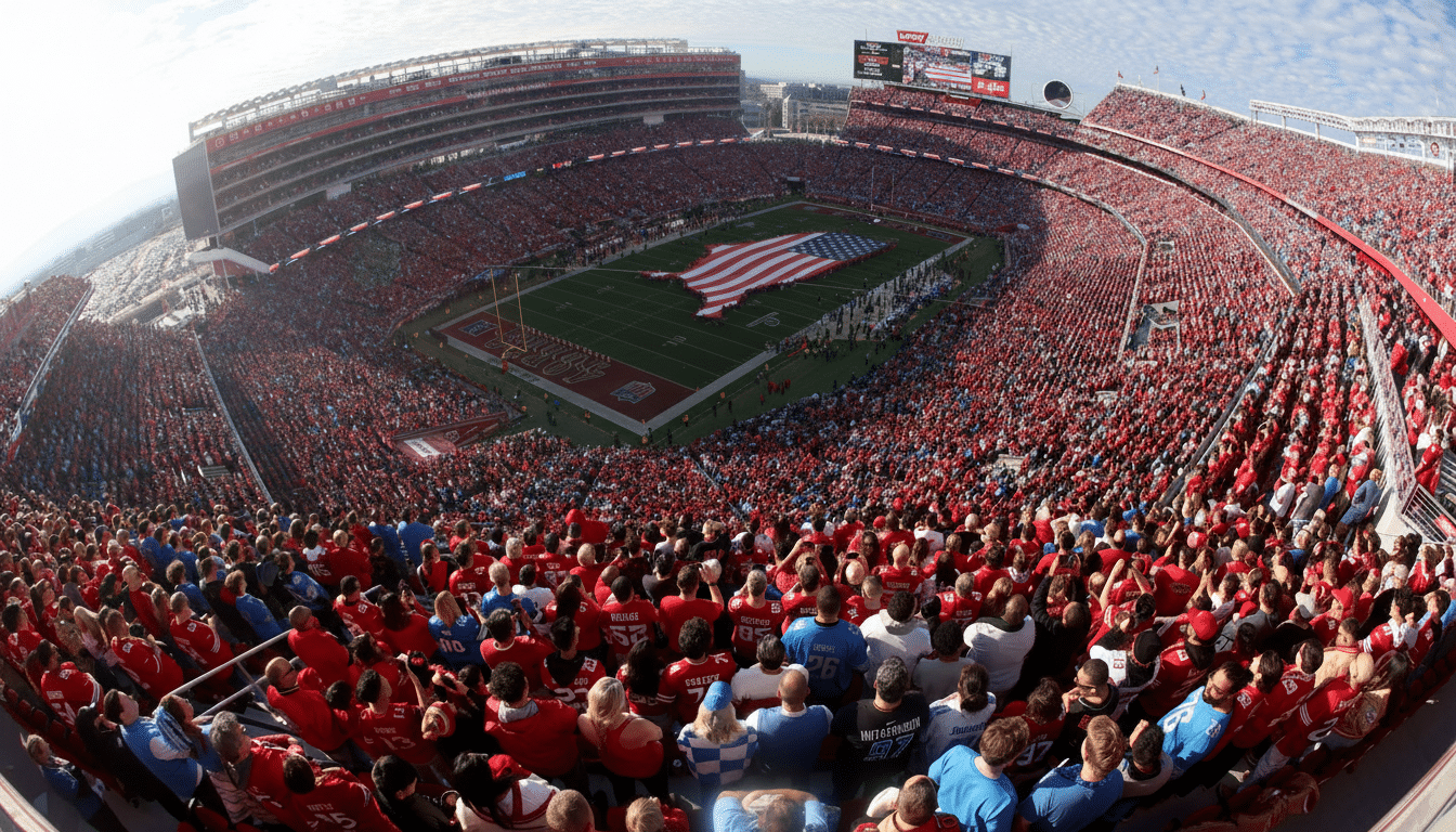 A wide-angle, high-angle shot of a packed football stadium, with the field displaying a large American flag. The stands are filled with a sea of fans, predominantly in red, under a partly cloudy sky.